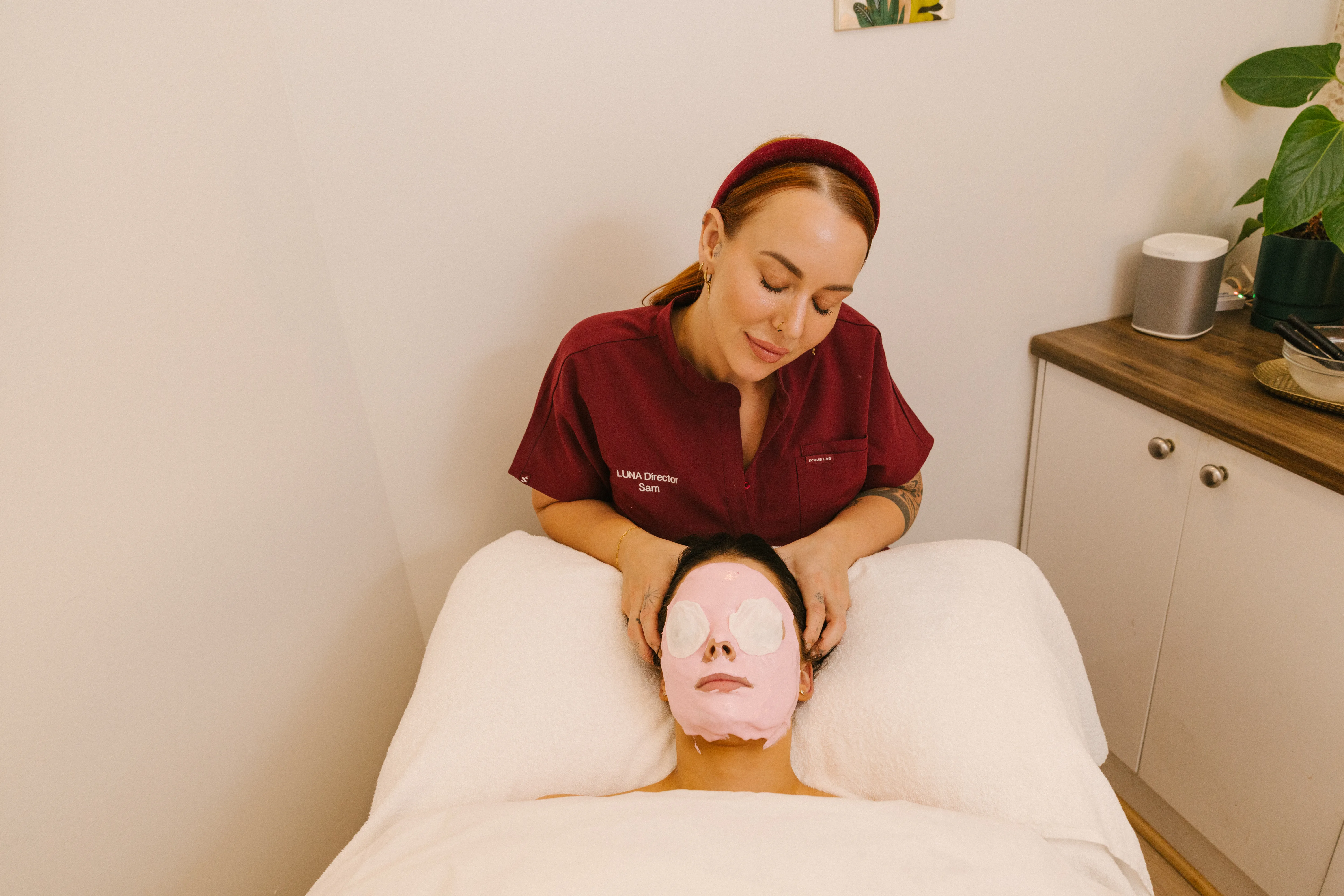 Therapist in LUNA uniform applying a sheet mask to a client during a skin treatment